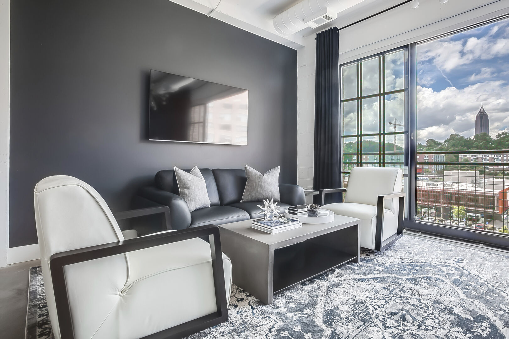 Living area with wall-mounted TV, sofa, two armchairs, and coffee table. Living area with wall-mounted TV, sofa, two armchairs, and coffee table.