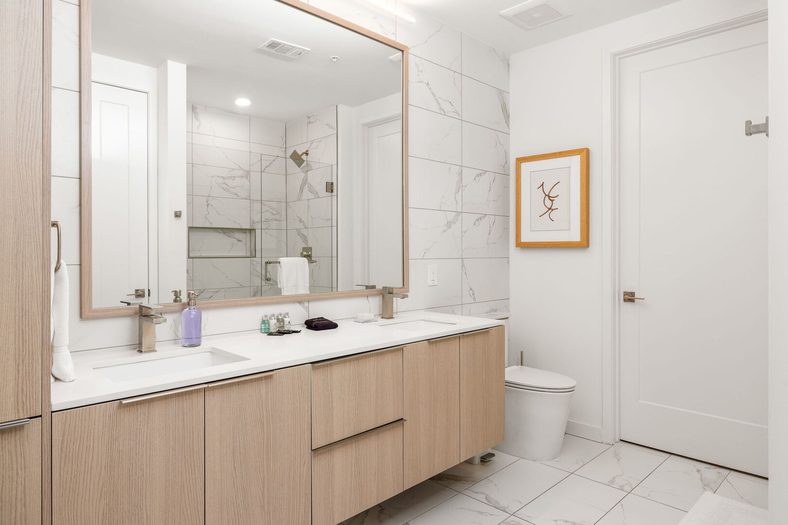 An en-suite bathroom featuring a double vanity and a spacious walk-in shower and closet