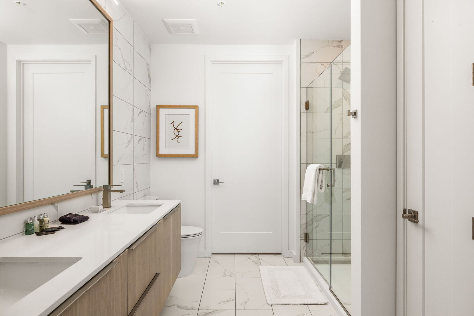 An en-suite bathroom featuring a double vanity and a spacious walk-in shower and closet