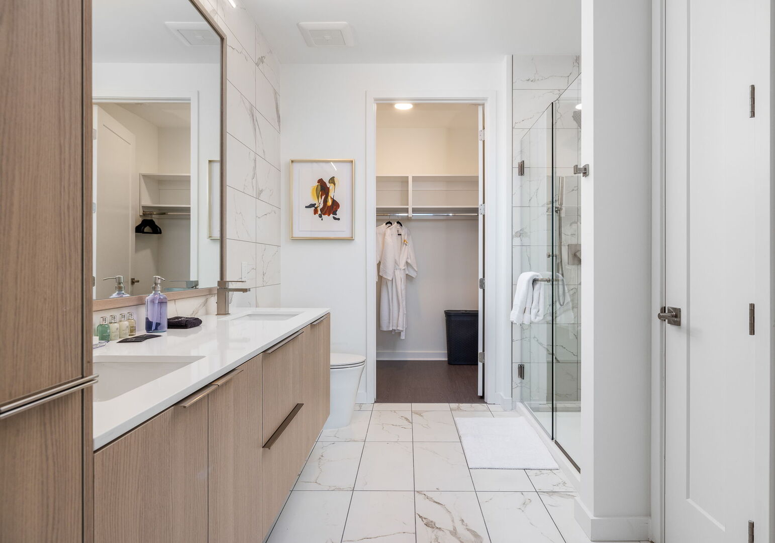 An en-suite bathroom featuring a double vanity and a spacious walk-in shower and closet