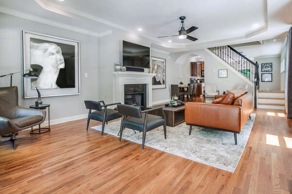 Arm Chairs, Sofa, Coffee Table, Fireplace, TV, Staircase, and Dining Set.