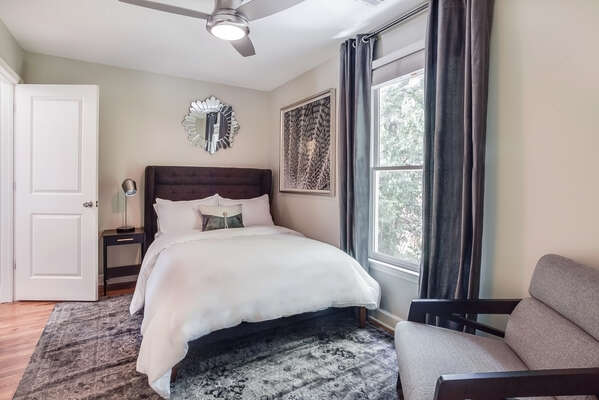 Bedroom with Large Bed, Ceiling Fan, Arm Chair, and Nightstand.