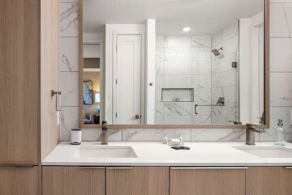 An en-suite bathroom featuring a double vanity and a spacious walk-in shower