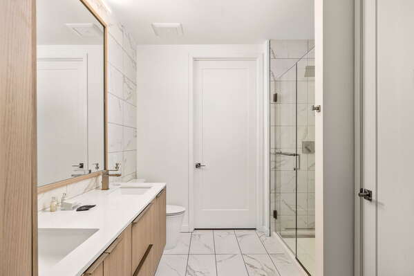 An en-suite bathroom featuring a double vanity and a spacious walk-in shower