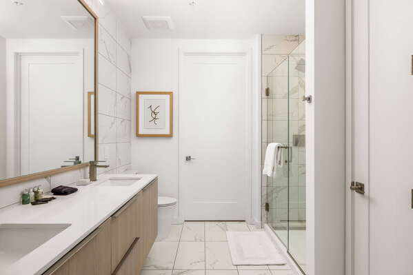 An en-suite bathroom featuring a double vanity and a spacious walk-in shower and closet
