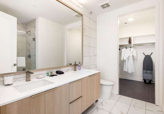An en-suite bathroom featuring a double vanity and a spacious walk-in shower and closet