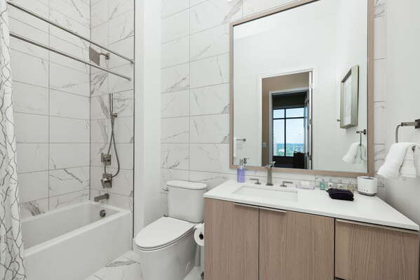 An en-suite bathroom featuring a single vanity and a spacious tub and shower.